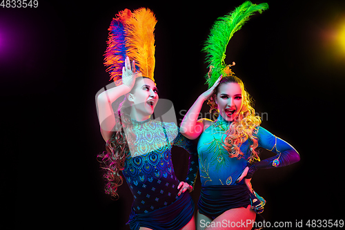 Image of Beautiful young women in carnival and masquerade costume in colorful neon lights on black background