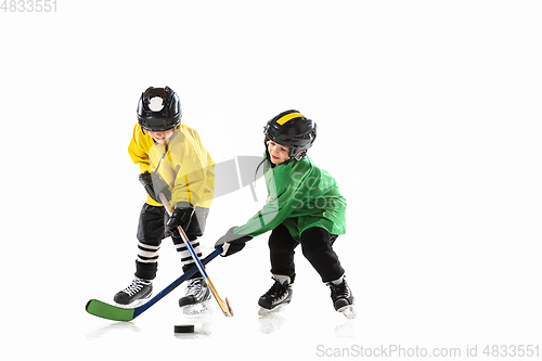 Image of Little hockey players with the sticks on ice court and white studio background