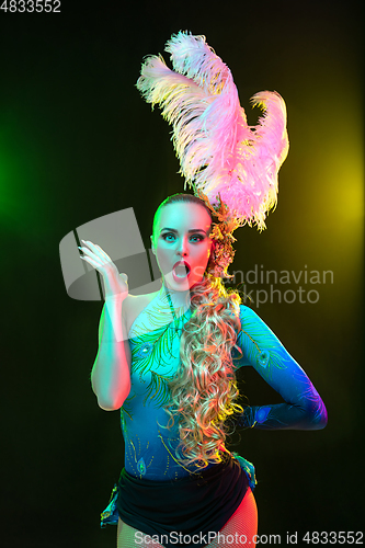 Image of Beautiful young woman in carnival and masquerade costume in colorful neon lights on black background