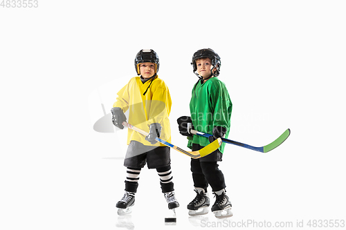 Image of Little hockey players with the sticks on ice court and white studio background