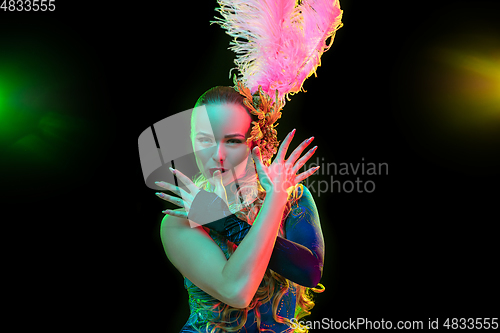 Image of Beautiful young woman in carnival and masquerade costume in colorful neon lights on black background