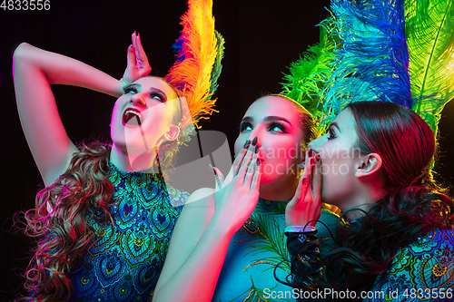 Image of Beautiful young women in carnival and masquerade costume in colorful neon lights on black background