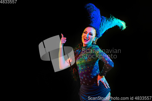 Image of Beautiful young woman in carnival and masquerade costume in colorful neon lights on black background