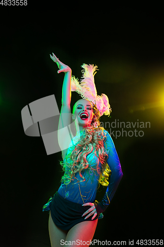 Image of Beautiful young woman in carnival and masquerade costume in colorful neon lights on black background