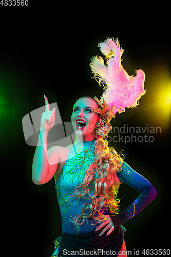 Image of Beautiful young woman in carnival and masquerade costume in colorful neon lights on black background