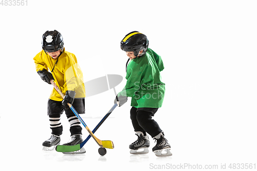 Image of Little hockey players with the sticks on ice court and white studio background