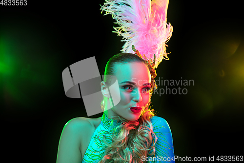 Image of Beautiful young woman in carnival and masquerade costume in colorful neon lights on black background