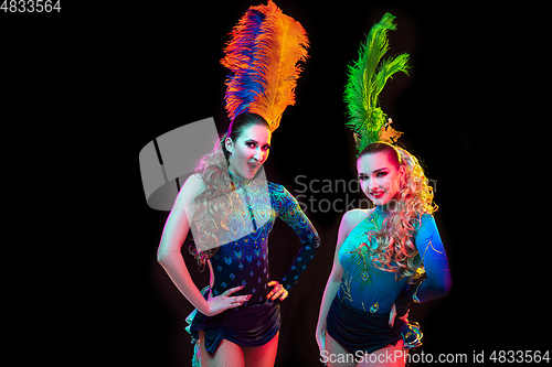 Image of Beautiful young women in carnival and masquerade costume in colorful neon lights on black background