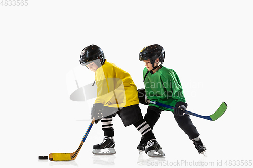 Image of Little hockey players with the sticks on ice court and white studio background