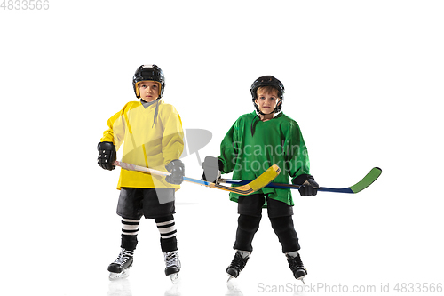 Image of Little hockey players with the sticks on ice court and white studio background