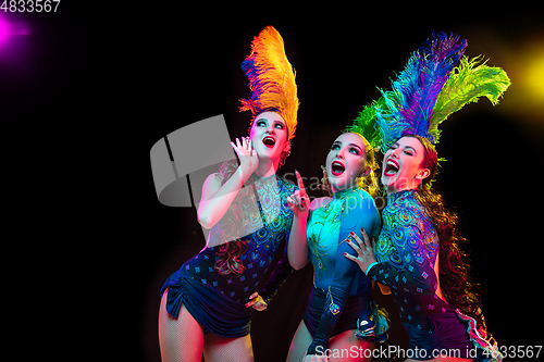 Image of Beautiful young women in carnival and masquerade costume in colorful neon lights on black background