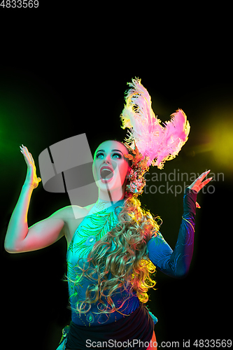 Image of Beautiful young woman in carnival and masquerade costume in colorful neon lights on black background