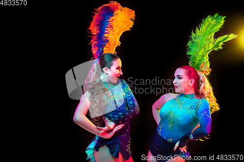 Image of Beautiful young women in carnival and masquerade costume in colorful neon lights on black background