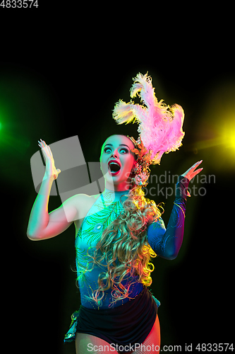 Image of Beautiful young woman in carnival and masquerade costume in colorful neon lights on black background