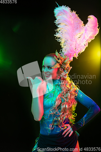 Image of Beautiful young woman in carnival and masquerade costume in colorful neon lights on black background