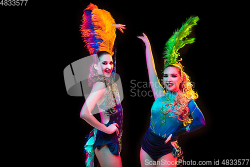 Image of Beautiful young women in carnival and masquerade costume in colorful neon lights on black background