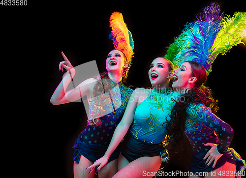 Image of Beautiful young women in carnival and masquerade costume in colorful neon lights on black background