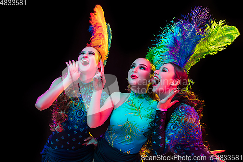 Image of Beautiful young women in carnival and masquerade costume in colorful neon lights on black background