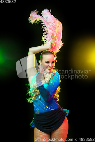 Image of Beautiful young woman in carnival and masquerade costume in colorful neon lights on black background