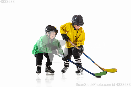 Image of Little hockey players with the sticks on ice court and white studio background