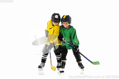 Image of Little hockey players with the sticks on ice court and white studio background