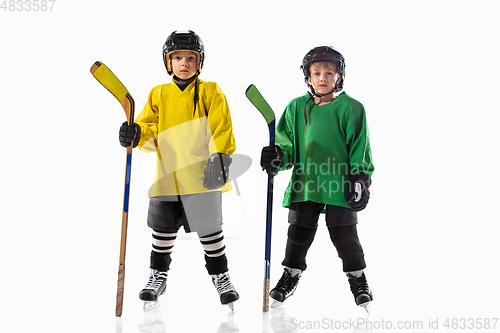 Image of Little hockey players with the sticks on ice court and white studio background