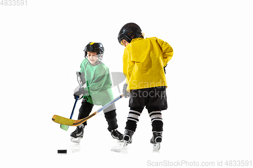 Image of Little hockey players with the sticks on ice court and white studio background