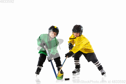 Image of Little hockey players with the sticks on ice court and white studio background