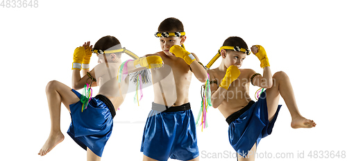 Image of Little boy exercising thai boxing on white background. Fighter practicing, training in martial arts in action, motion. Evolution of movement, catching moment.