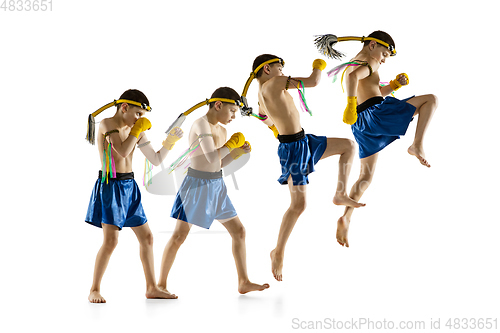 Image of Little boy exercising thai boxing on white background. Fighter practicing, training in martial arts in action, motion. Evolution of movement, catching moment.