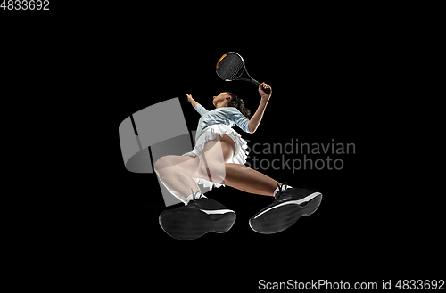 Image of Female professional tennis player in action, motion isolated on black background, look from the bottom. Concept of sport, movement, energy and dynamic.