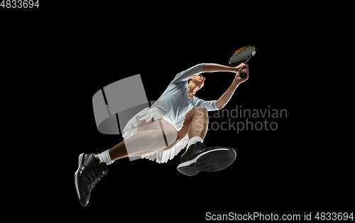 Image of Female professional tennis player in action, motion isolated on black background, look from the bottom. Concept of sport, movement, energy and dynamic.