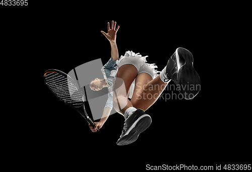 Image of Female professional tennis player in action, motion isolated on black background, look from the bottom. Concept of sport, movement, energy and dynamic.