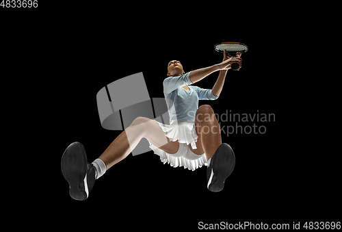 Image of Female professional tennis player in action, motion isolated on black background, look from the bottom. Concept of sport, movement, energy and dynamic.