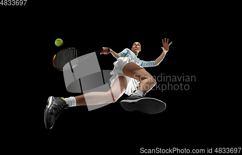 Image of Female professional tennis player in action, motion isolated on black background, look from the bottom. Concept of sport, movement, energy and dynamic.