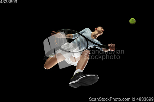 Image of Female professional tennis player in action, motion isolated on black background, look from the bottom. Concept of sport, movement, energy and dynamic.