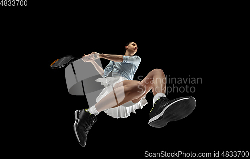 Image of Female professional tennis player in action, motion isolated on black background, look from the bottom. Concept of sport, movement, energy and dynamic.