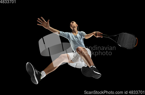 Image of Female professional tennis player in action, motion isolated on black background, look from the bottom. Concept of sport, movement, energy and dynamic.