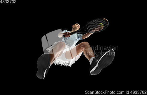 Image of Female professional tennis player in action, motion isolated on black background, look from the bottom. Concept of sport, movement, energy and dynamic.