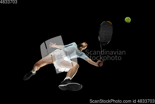 Image of Female professional tennis player in action, motion isolated on black background, look from the bottom. Concept of sport, movement, energy and dynamic.