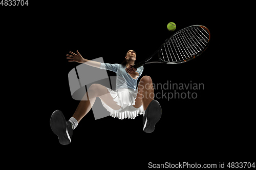 Image of Female professional tennis player in action, motion isolated on black background, look from the bottom. Concept of sport, movement, energy and dynamic.