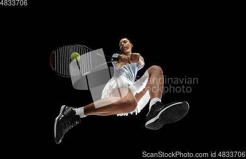 Image of Female professional tennis player in action, motion isolated on black background, look from the bottom. Concept of sport, movement, energy and dynamic.