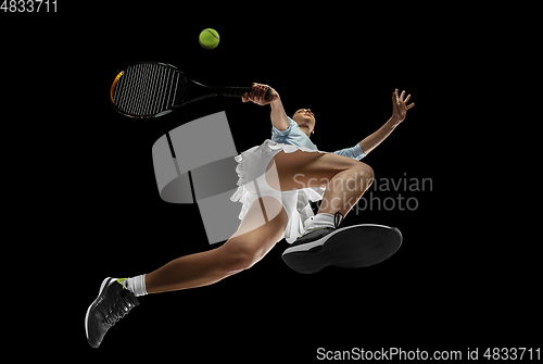 Image of Female professional tennis player in action, motion isolated on black background, look from the bottom. Concept of sport, movement, energy and dynamic.