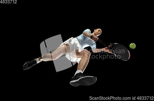 Image of Female professional tennis player in action, motion isolated on black background, look from the bottom. Concept of sport, movement, energy and dynamic.