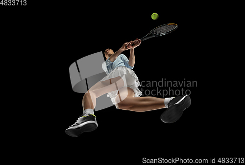 Image of Female professional tennis player in action, motion isolated on black background, look from the bottom. Concept of sport, movement, energy and dynamic.