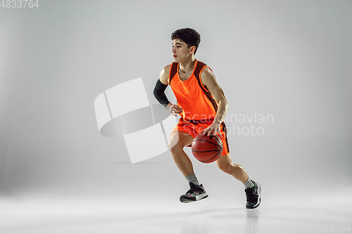 Image of Young basketball player training isolated on white studio background