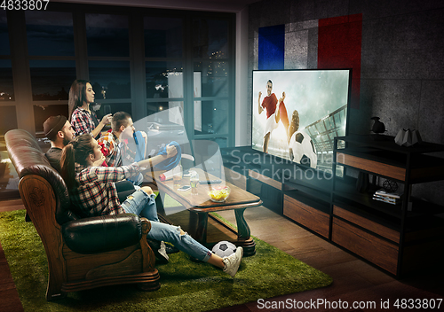 Image of Group of friends watching TV, football match in France, sport games