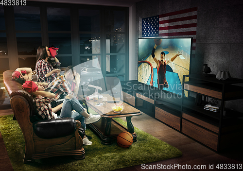 Image of Group of friends watching TV, basketball match in America, sport games