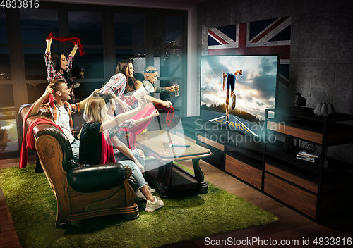 Image of Group of friends watching TV, run competition in Great Britain, sport games