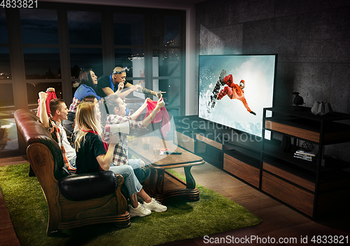 Image of Group of friends watching TV, snowboarding sport games